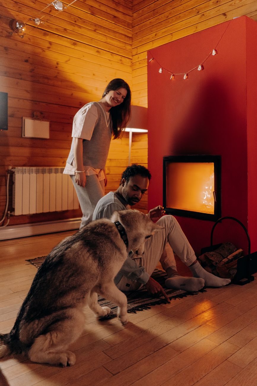Couple and their dog relaxing in a warm living room by the fire